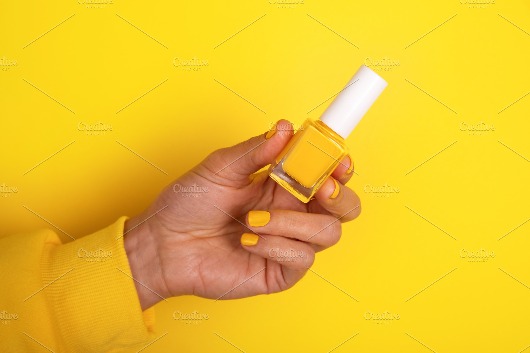 Hand holding yellow nail polish bottle on vibrant yellow backgro, a Beauty & Fashion Photo by Ales Munt