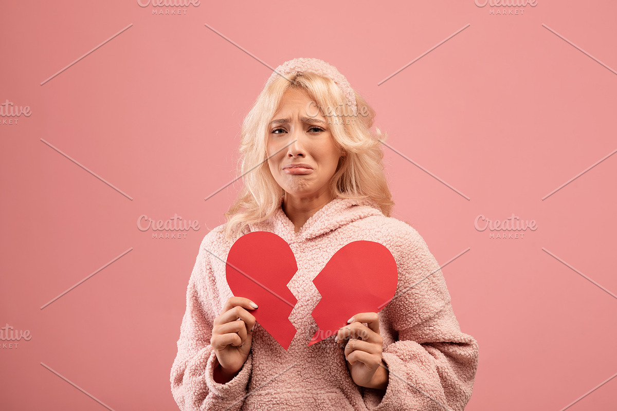 Unhappy lady holding two halves of cut paper heart and crying, feeling hurt, go, a Photo by Prostock-Studio (Photo 2 of 2)