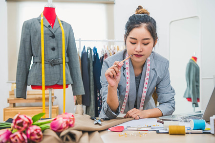 Attractive Asian female fashion designer working in home office, a Person Photo by Ministocker