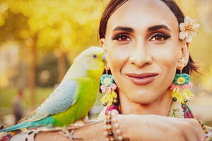 Trans woman with budgerigar at urban park, a Person Photo by DanFLCreativo