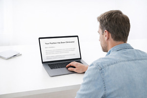Man reading layoff notification on a, a Photo by Dvoevnore photos