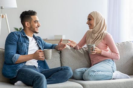 Muslim couple drinking tea and talking at home, a Photo by Prostock-Studio