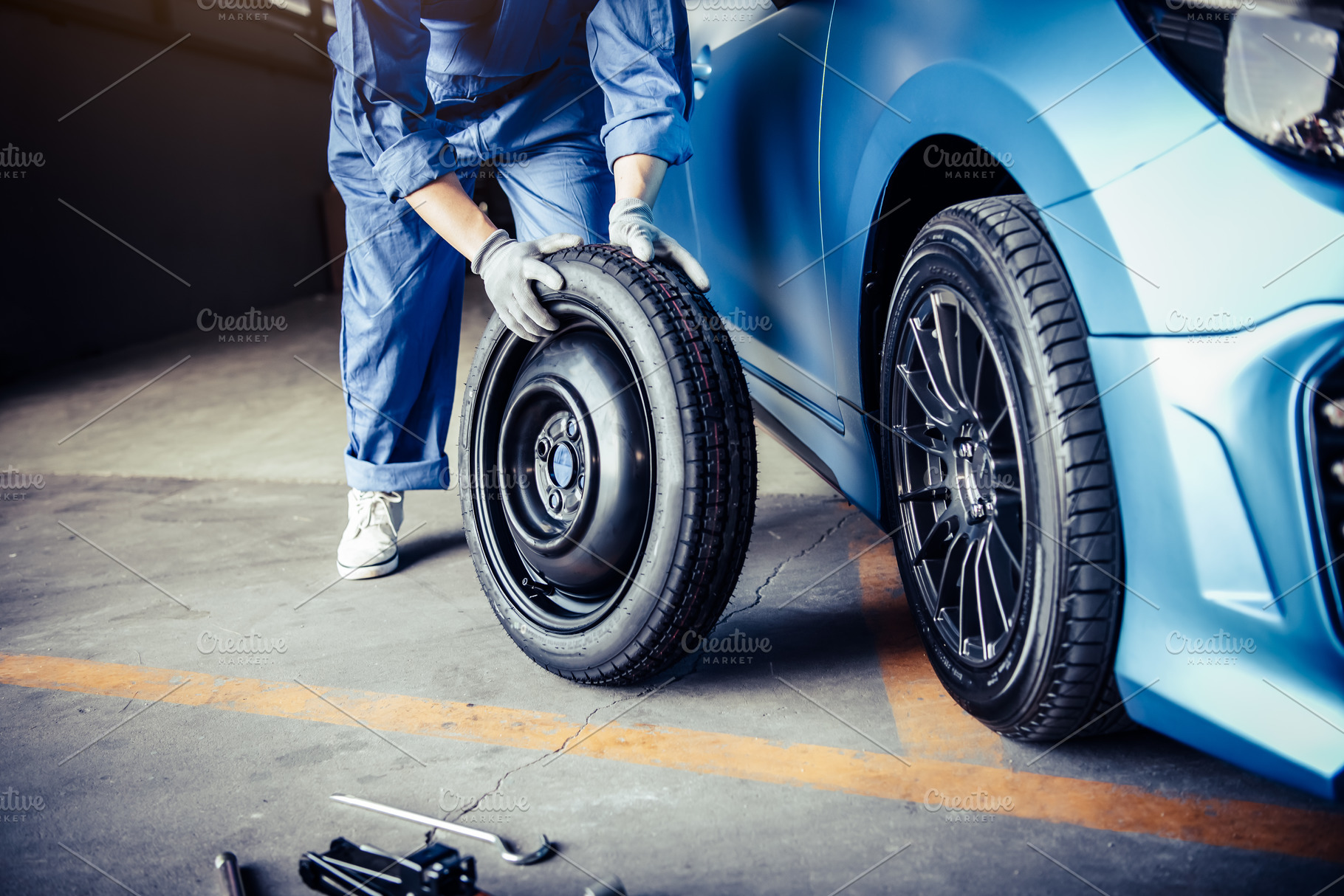 Car mechanics changing tire at auto repair shop garage. Transpor, an Industrial Photo by Ministocker