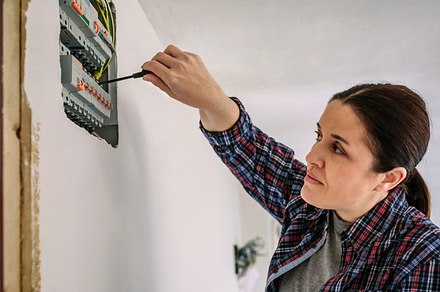 Electrician working on the distribution panel of a house, an Industrial Photo by davidpereiras