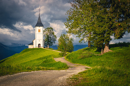 Winding rural road and small church, an Architecture Photo by Alpine Dreams