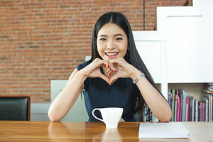 Asian woman smiling in front of coffee on the table stock photo containing
