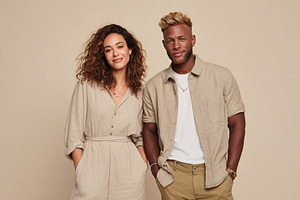 Stylish couple poses together in neutral-toned clothing against a plain backgro, a Photo by AlyaAnd
