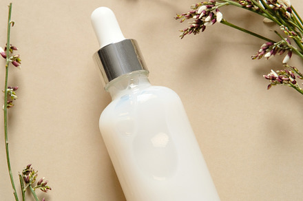 Face serum bottle with flowers on beige background. Natural cosmetics., a Health & Medical Photo by photoguns