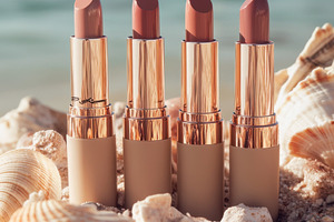 Lipsticks on a beach with seashells, a Photo by Beautiful things