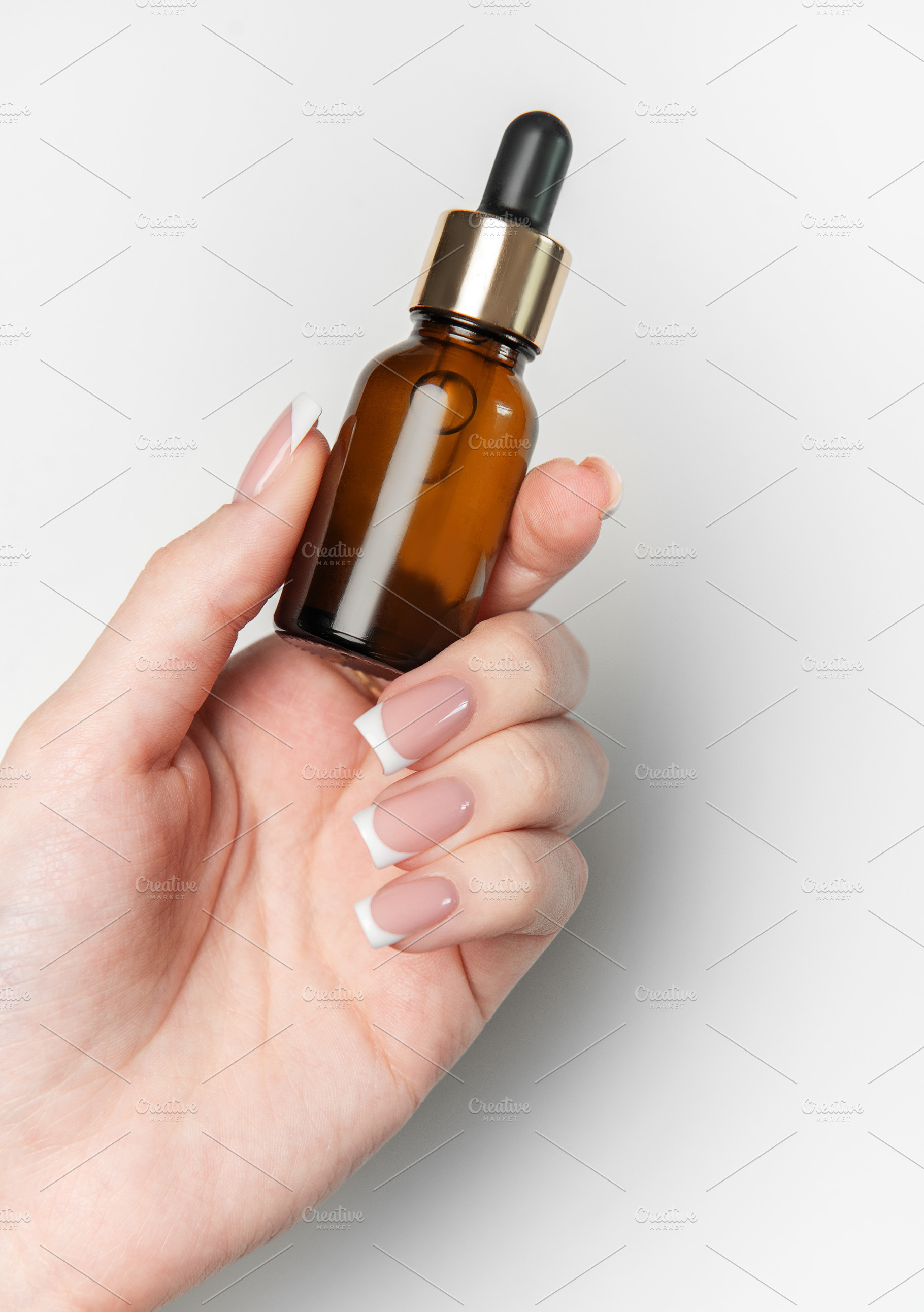 Woman hand holding cosmetic dropper bottle on white background, a Beauty & Fashion Photo by Olena Rudo