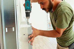 Construction worker installing metal corner bead on drywall with cordless screw, an Industrial Photo by Antonio Gravante Market