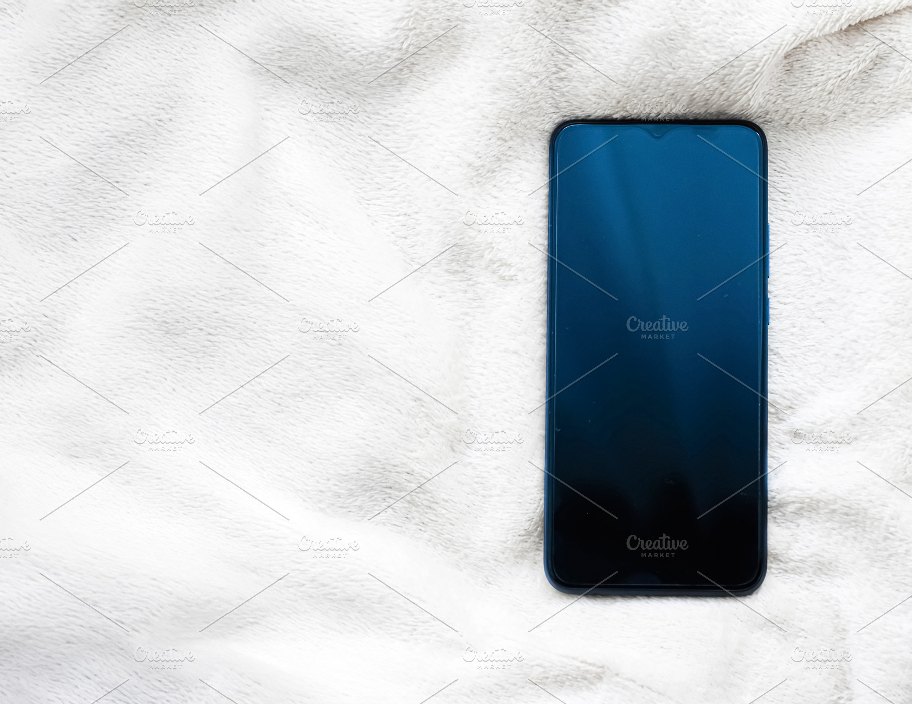 Smartphone resting on a soft white blanket, flat lay for comfort, technology, a, a Photo by Studio ANNA