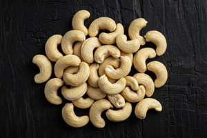 Raw cashew nuts arranged on a dark t, a Food & Drink Photo by professorinc