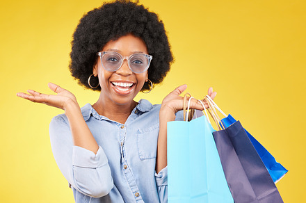 Shopping bag, retail portrait and black woman with sales product, discount fashion deal or mall store present. Commerce market, luxury designer gift and happy customer isolated on yellow background, a Photo by Peopleimages.com