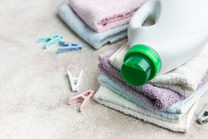 Laundry detergent bottle on a stack of clean towels, an Industrial Photo by Olena Rudo