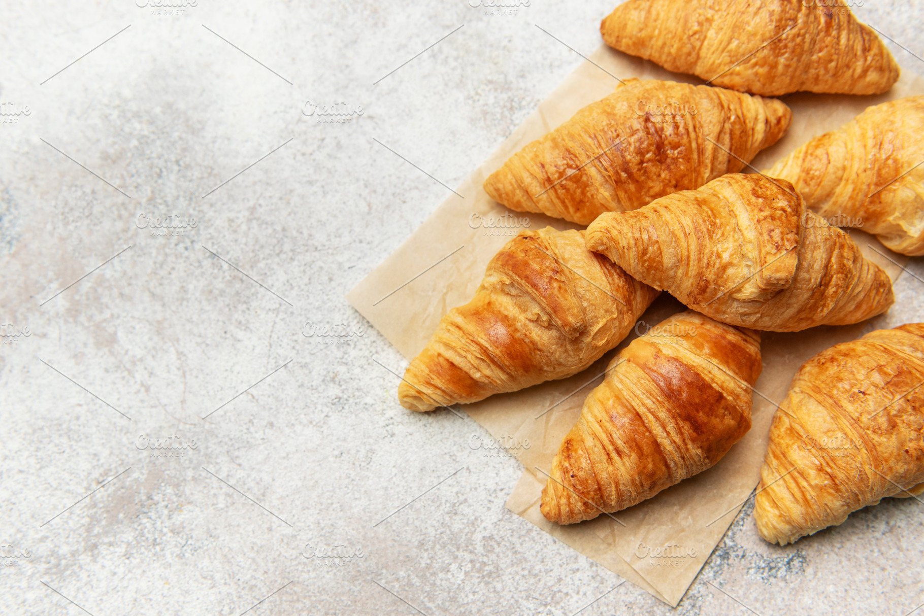 Freshly baked croissants resting on baking paper, a golden pastr, a Food & Drink Photo by Olena Rudo