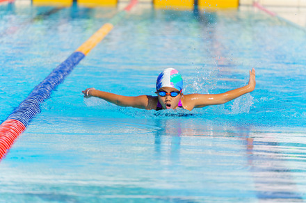 Swimmer child swims butterfly swimming style in a race swimming