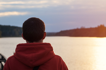 A man in an orange hoodie looks at a cloudy autumn sunset by the lake. Lifestyl, a Person Photo by PavelKant
