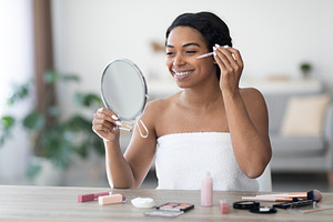 Attractive black woman applying concealer after shower