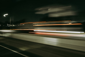 Light trails of a moving vehicle at night on the road, a Background Photo by GoodGoods