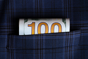 Rolled one hundred dollar bill tucked into a blue plaid suit pocket, symbolizin, a Business Photo by Ales Munt
