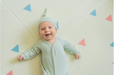 Adorable baby in a green hat lying, a Person Photo by Elizaveta Galitskaya