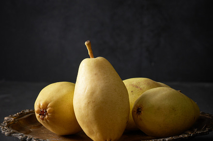 ripe green pears on a metal plate, black background, a Photo by ndanko