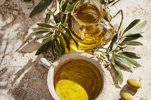 Olive oil in ceramic bowl and glass pitcher with green olives an, a Photo by Studio ANNA