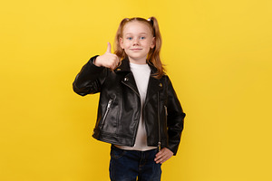 Smiling young girl in a black leather jacket giving a thumbs-up, a Person Photo by Ales Munt