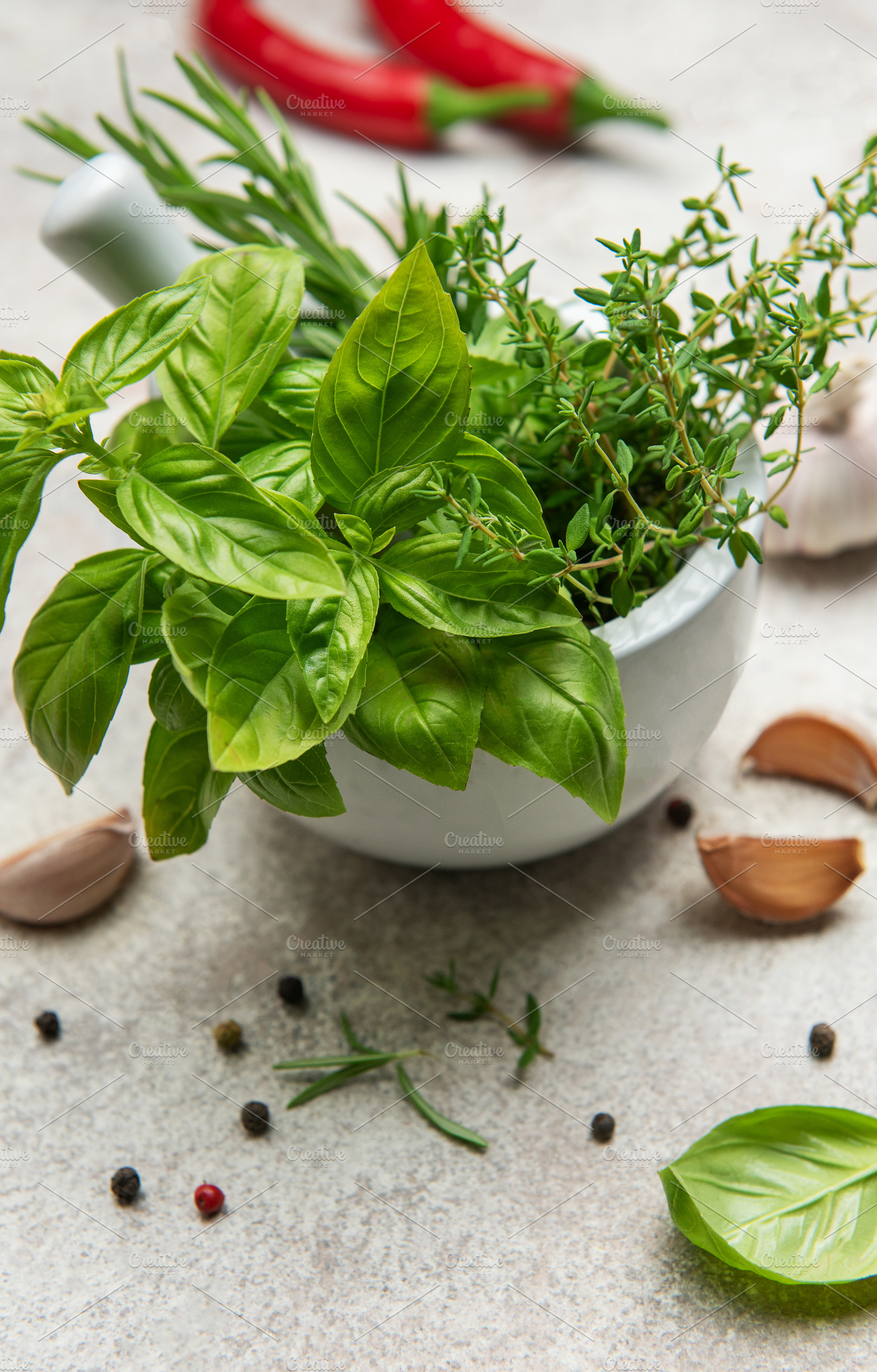 Fresh herbs and spices in mortar with pestle on kitchen table, a Food & Drink Photo by Olena Rudo