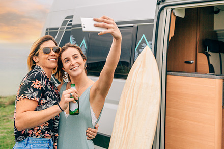 Two friends taking a selfie with their cellphone next to their campervan during, a Holiday Photo by davidpereiras