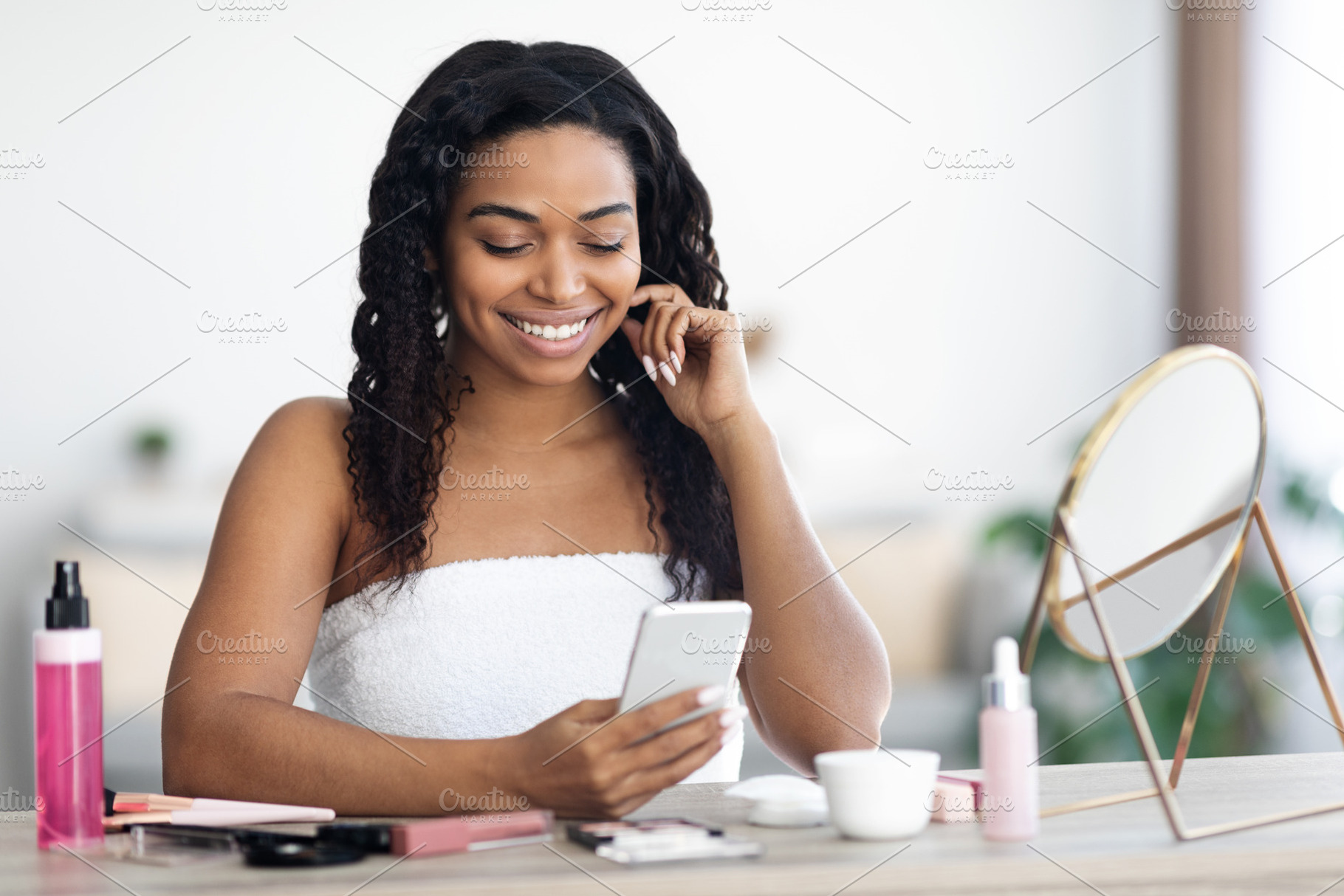 Cheerful naked african american woman using smartphone, reading beauty blog, a Photo by Prostock-Studio