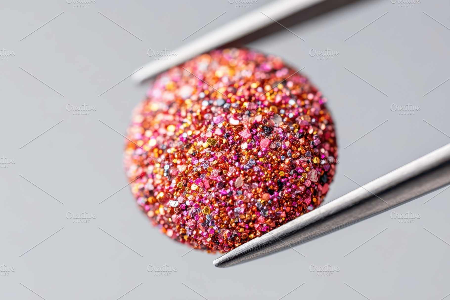 Glittery round object held with tweezers, an Abstract Photo by AlyaAnd