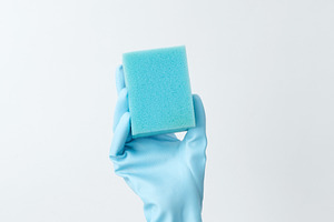 Hand in blue rubber glove holding a sponge for cleaning. Household cleaning and, a Photo by matucha