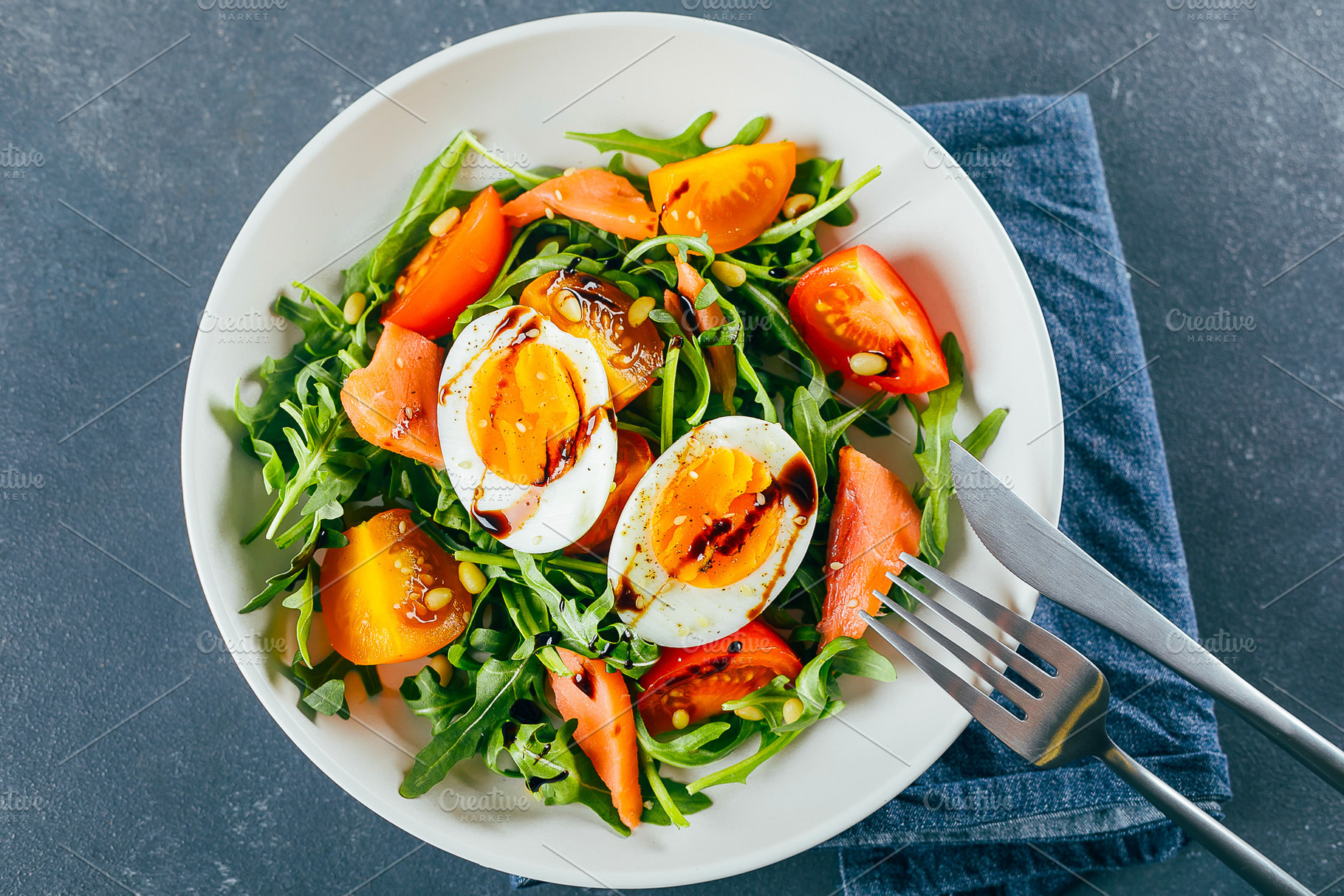 Healthy vegan salad of fresh tomato, arugula, salmon, egg and sesame on plate., a Food & Drink Photo by Anikona