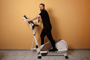 Bearded man in black sportswear exercising on elliptical machine, a Person Photo by Ales Munt