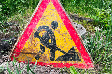Weathered construction sign placed in a grassy area under bright daylight condi, a Photo by AS photostudio
