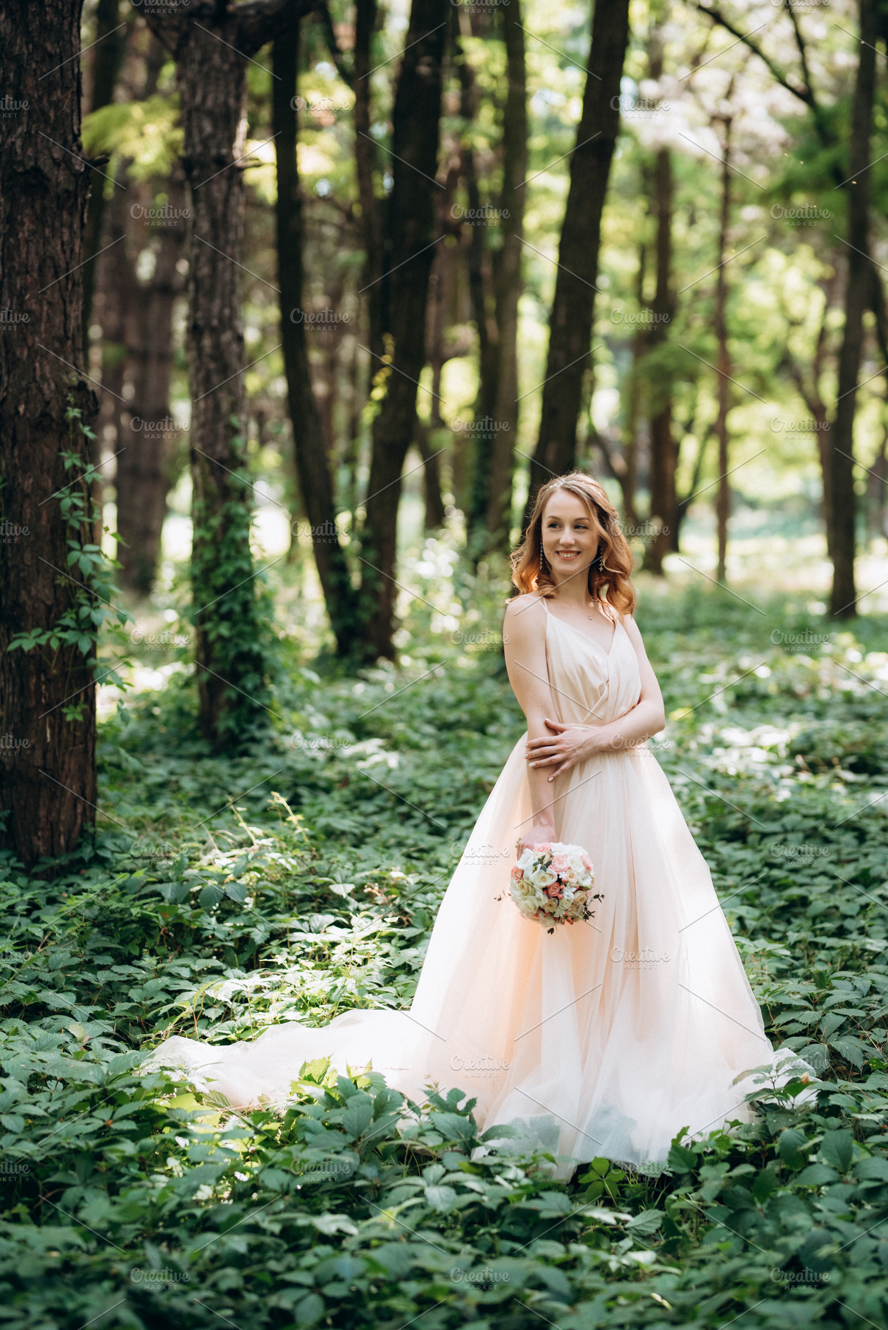 Blonde bride in a light coral dress in a green forest, a Person Photo by Weddings, People, Travel