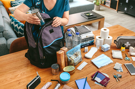 Woman putting cans of food to prepare emergency backpack, a Health & Medical Photo by davidpereiras