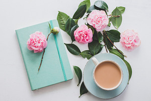 Flatlay of tea, blue journal, flower, a Business Photo by René Jordaan Photography
