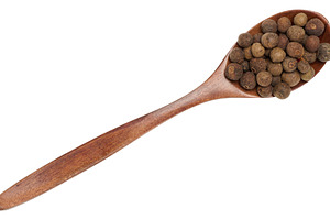 Allspice peas in a wooden brown spoon on an isolated background, a Food & Drink Photo by ndanko