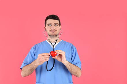 Nurse man holds red heart on pink background, a Person Photo by AtlasStudio PRO