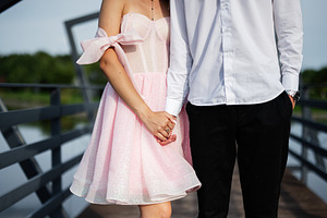 Couple holding hands on scenic bridge wearing stylish elegant outfits, a Photo by AS photostudio