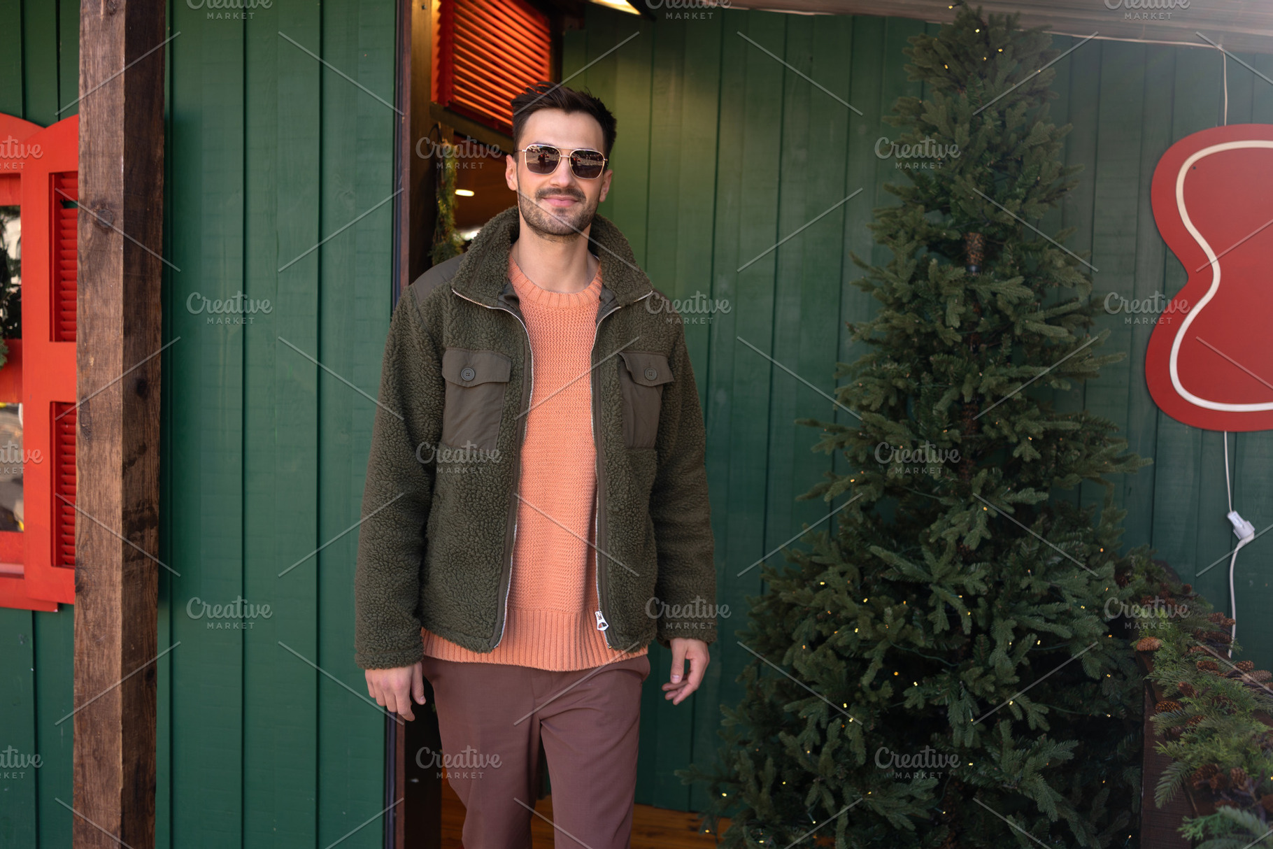Handsome man in jacket standing outside green house during Christmas, a Person Photo by andreonegin market