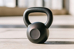 Kettlebell resting on gym floor in bright fitness studio during morning workout, a Photo by AlyaAnd