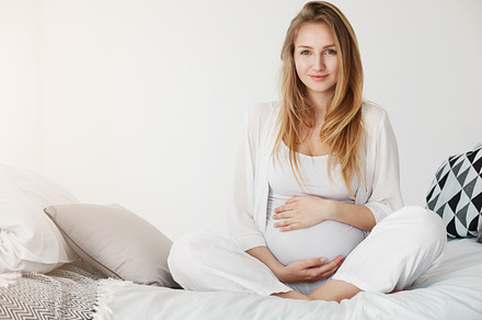 Healthy pregnancy gestation. Portrait of a young pregnant smiling woman sitting in her bedroom resting in the morning holding her tummy waiting for her childbirth., a Person Photo by ringsaroundme