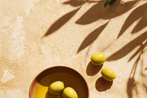 Green olives floating in olive oil bowl on a mediterranean style, a Photo by Studio ANNA
