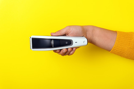 Hand holding an electric hair trimmer horizontally against bold