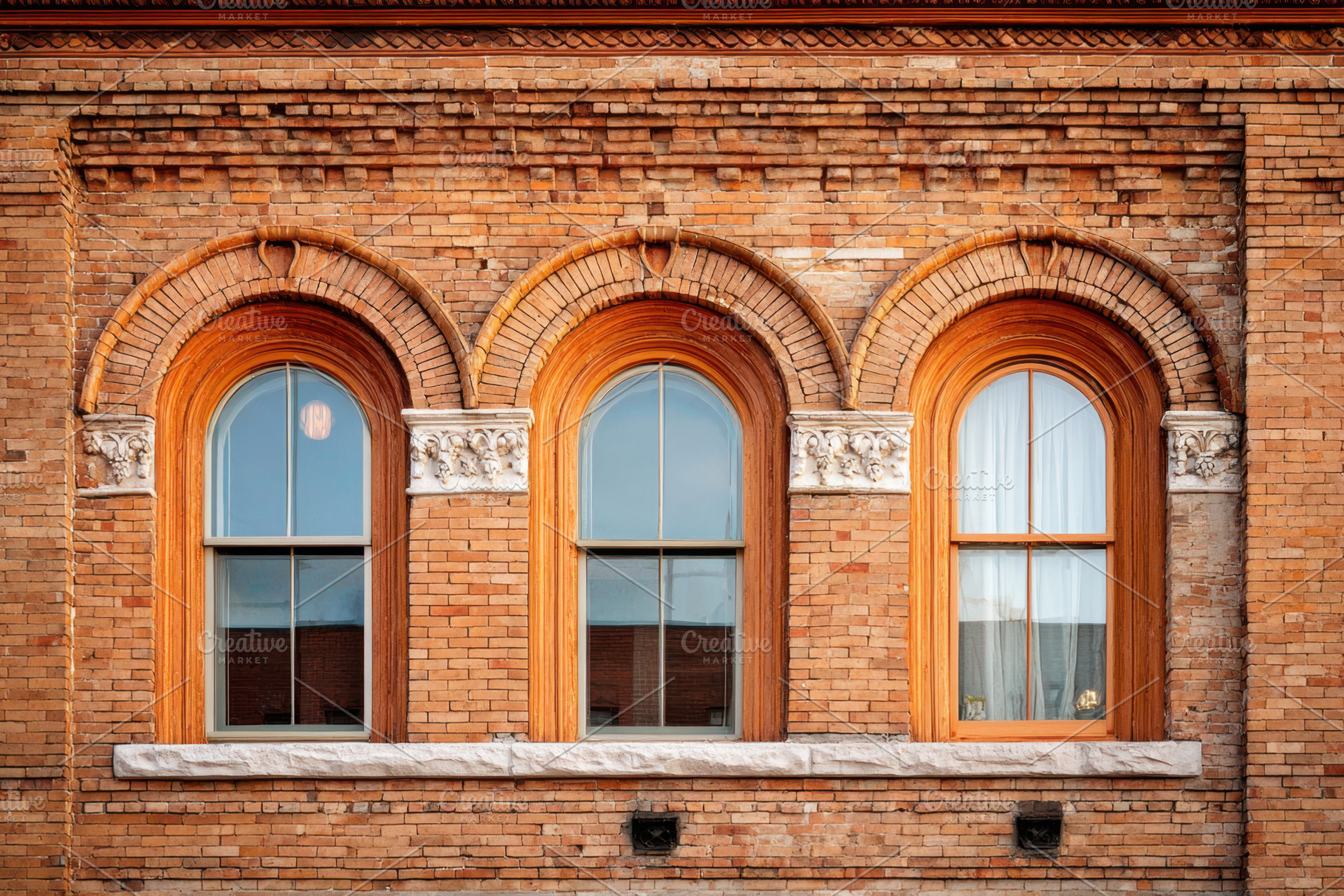 Ornate windows on a vintage brick facade, an Architecture Photo by AlyaAnd