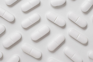 White oval pills scattered on a bright uniform surface represent, a Photo by Studio ANNA